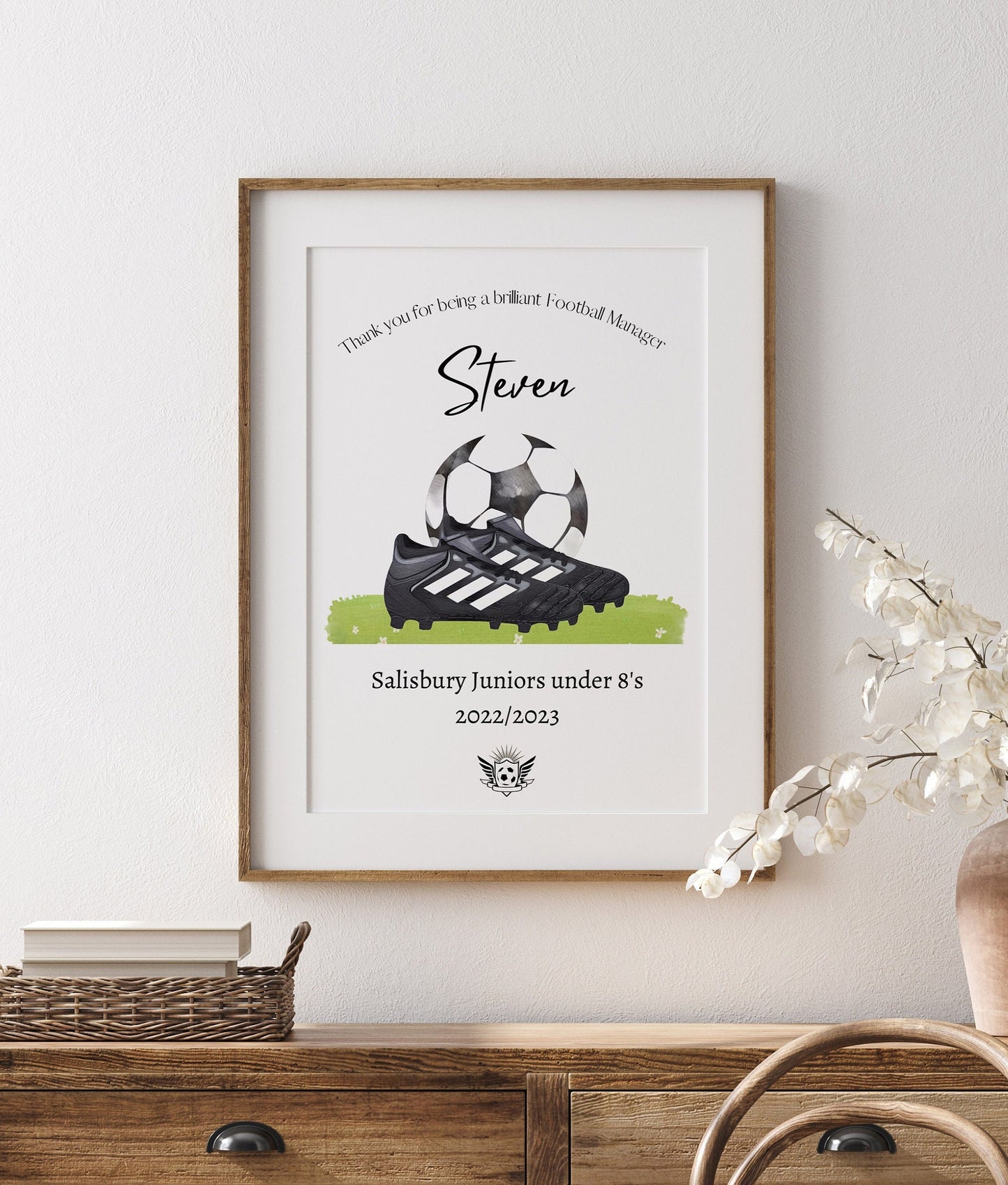 Personalised football print featuring the title ‘Coach’ or ‘Manager’ with the recipient’s name, team name, year, and team logo. The design includes a watercolour-style illustration of a football boot and ball, combining text and imagery in a sporty, artistic layout.