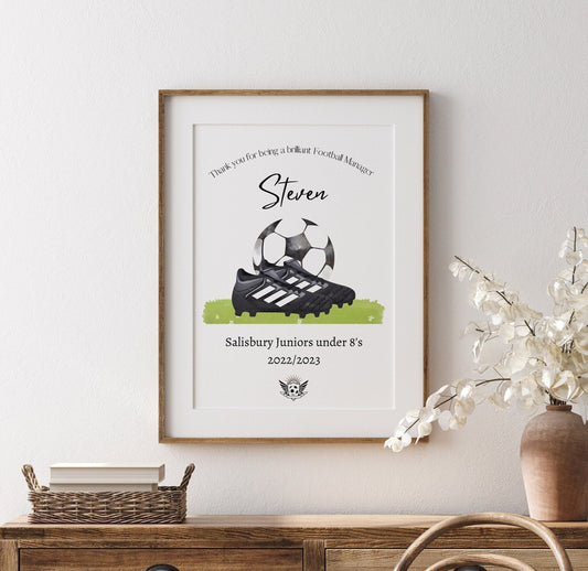Personalised football print featuring the title ‘Coach’ or ‘Manager’ with the recipient’s name, team name, year, and team logo. The design includes a watercolour-style illustration of a football boot and ball, combining text and imagery in a sporty, artistic layout.