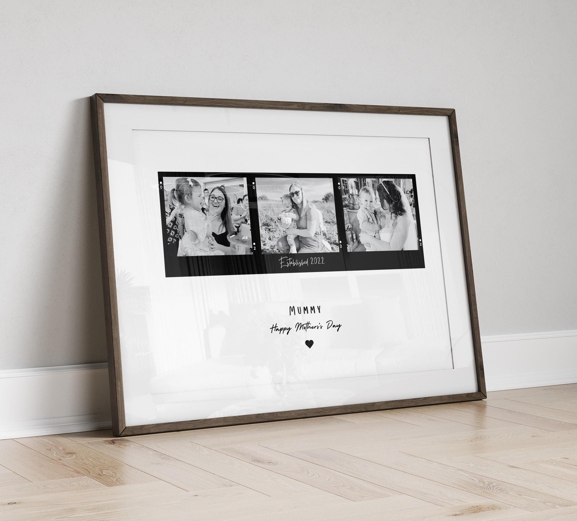 A framed black and white print featuring three candid mother-child photographs arranged in a film strip style. The center of the print includes the text &quot;Established date.&quot; Below the images, Mum, Mummy, Mamma etc can be added. The frame can be black or white and the background is minimalistic.