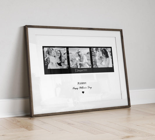 A framed black and white print featuring three candid mother-child photographs arranged in a film strip style. The center of the print includes the text &quot;Established date.&quot; Below the images, Mum, Mummy, Mamma etc can be added. The frame can be black or white and the background is minimalistic.